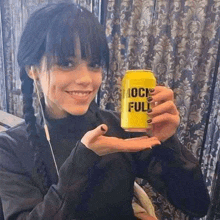 a young woman is holding a yellow can of beer in her hand .