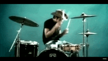 a man wearing a cowboy hat is playing drums and smoking a cigarette .