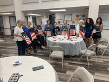 a group of people are standing around a table holding flags