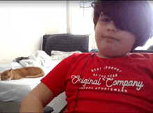 a young boy wearing a red shirt that says original company