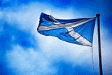 the scottish flag is waving in the wind against a blue sky .