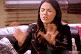 a woman in a leather jacket is sitting on a couch and making a face