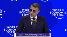 a man in a suit and tie stands at a podium at the world economic forum
