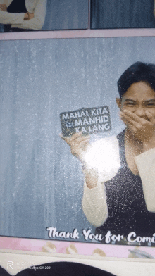 a man holding a sign that says mahal kita