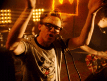 a man singing into a microphone wearing a mickey mouse shirt
