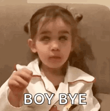 a little girl is sitting on a couch eating a piece of cake and making a face .