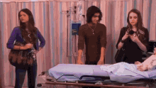 a group of people standing around a hospital bed with a drip on it