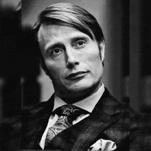 a black and white photo of a man in a suit and tie looking up .