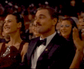 a man in a tuxedo sitting in a crowd of people