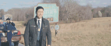 a man in a suit and tie is standing in front of a sign that says welcome to hartview .