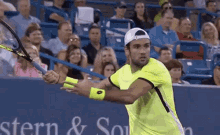 a man in a yellow shirt is holding a tennis racquet in front of a sign that says stern & southern