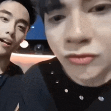 a close up of two men 's faces with a microphone in their mouth .