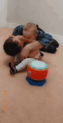 a baby is laying on a man 's lap with a toy drum in the background