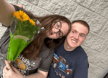 a girl holding a bouquet of sunflowers next to a boy wearing a shirt that says shville on it