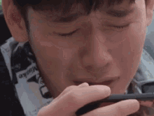 a young man is crying while looking at his phone .