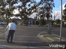 a man in a white shirt is walking across an intersection with a sign that says ' no parking '