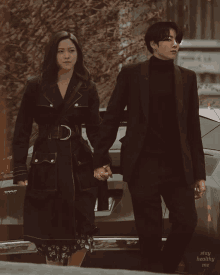 a man and a woman are holding hands in front of a car that says too on it