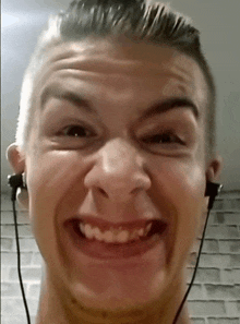 a young man wearing ear buds is smiling and making a funny face