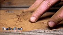 a close up of a person 's finger on a piece of wood with the words that is all rust written above it