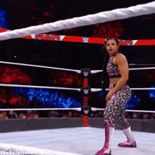 a woman is standing in a wrestling ring with a rope around her waist .