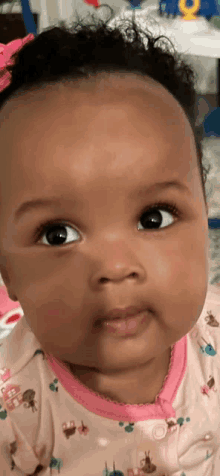 a close up of a baby 's face wearing a pink outfit