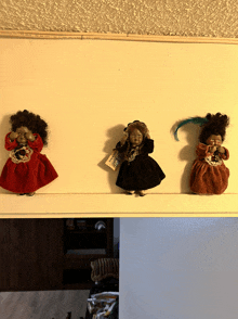 three dolls are hanging on a wall and one has a tag that says ' antique '