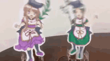 two paper dolls are standing next to each other on a table . one of the dolls is wearing a purple dress .