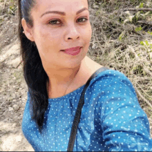 a woman wearing a blue polka dot top is smiling