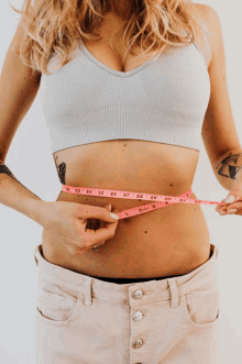 a woman measuring her waist with a tape measure that goes up to 30