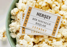 a bowl of popcorn has two tickets that say hersey on them