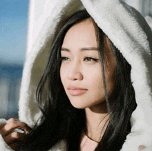 a woman wearing a white hooded jacket is looking out a window