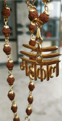 a gold necklace with a pendant that says mahakal on it