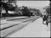 a black and white photo of a train station with a sign that says ' s. simpson 's ' on it