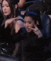 a group of women are sitting in a stadium watching a game and one of them is making a funny face .