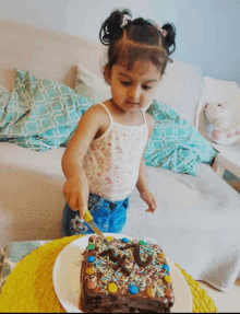 a little girl is cutting a birthday cake with a knife and sprinkles