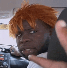 a man with orange hair is sitting in a car