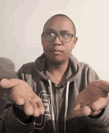 a man wearing glasses and a gray sweatshirt with the letter u on it