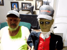 a man wearing a kenworth baseball cap stands next to a puppet