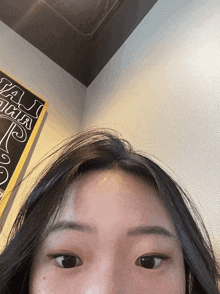 a close up of a woman 's face in front of a chalkboard that says ' a ' on it