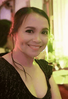 a woman in a black dress smiles at the camera