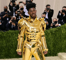 a man in a gold suit is standing in front of a crowd of people taking pictures