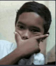 a boy is covering his mouth with his hand .