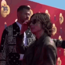 a man and a woman are standing next to each other on a red carpet at a movie awards event .