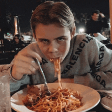 a boy in a balenciaga sweater is eating spaghetti