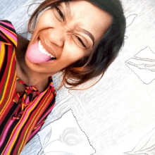 a woman in a striped shirt is sticking out her tongue