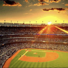 a baseball stadium with the sun shining through the clouds above