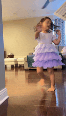 a little girl in a purple dress is dancing on the floor