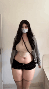 a woman wearing a mask and shorts is standing in front of a wall