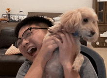 a man wearing glasses is holding a small dog in his arms