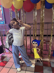 a little girl stands in front of balloons and a cartoon character